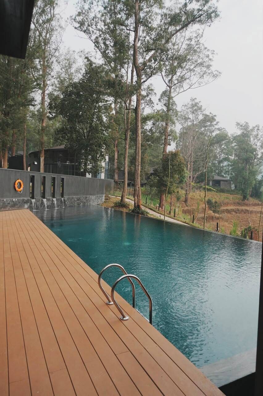 Eine Holzterrasse führt zu einem Schwimmbecken mit Rettungsboje und Wasserfall.