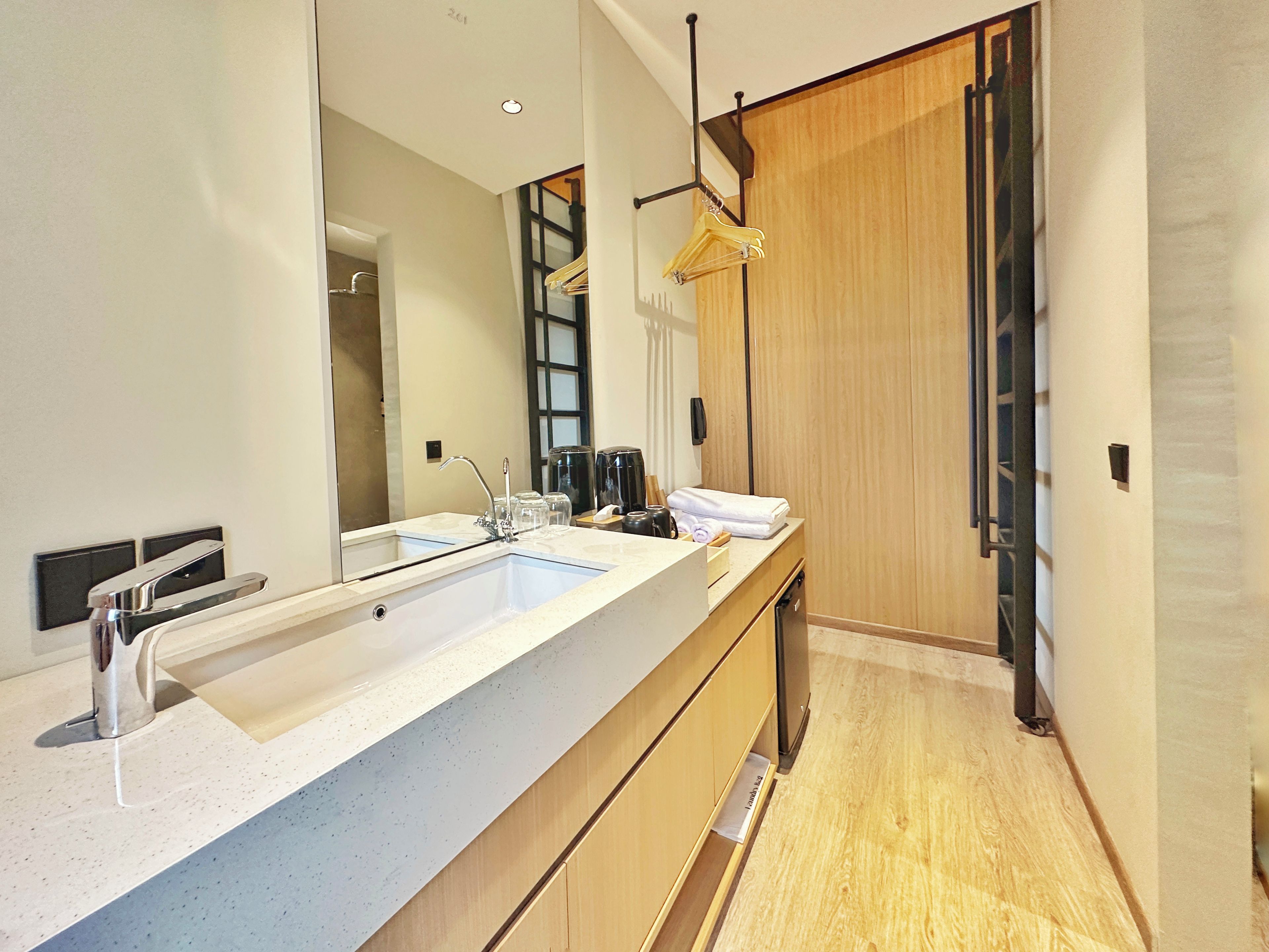 A modern bathroom with a large sink, mirror, and wooden vanity.