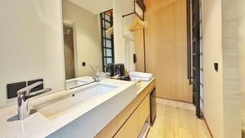 A modern bathroom with a large sink, mirror, and wooden vanity.