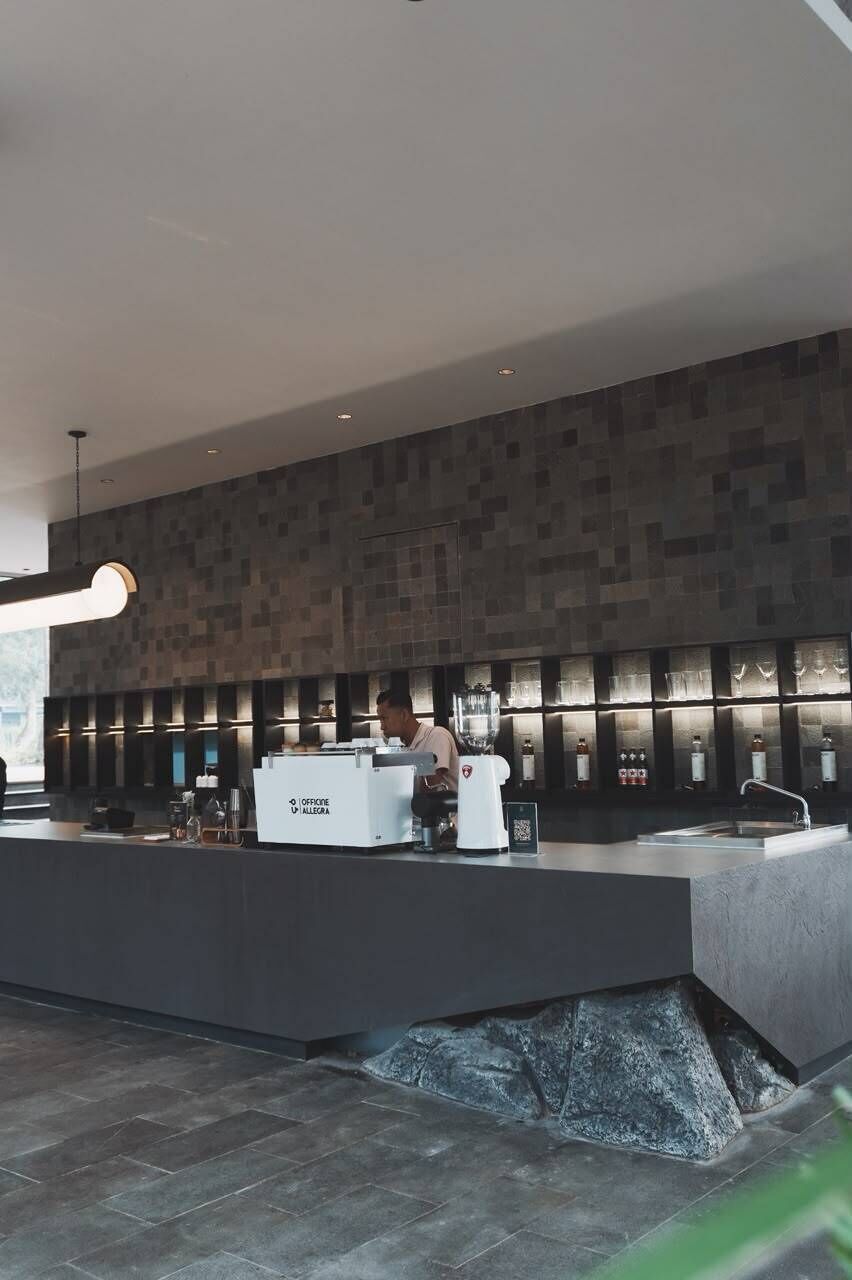 Een moderne bar met een toog, barstoelen en een barman.