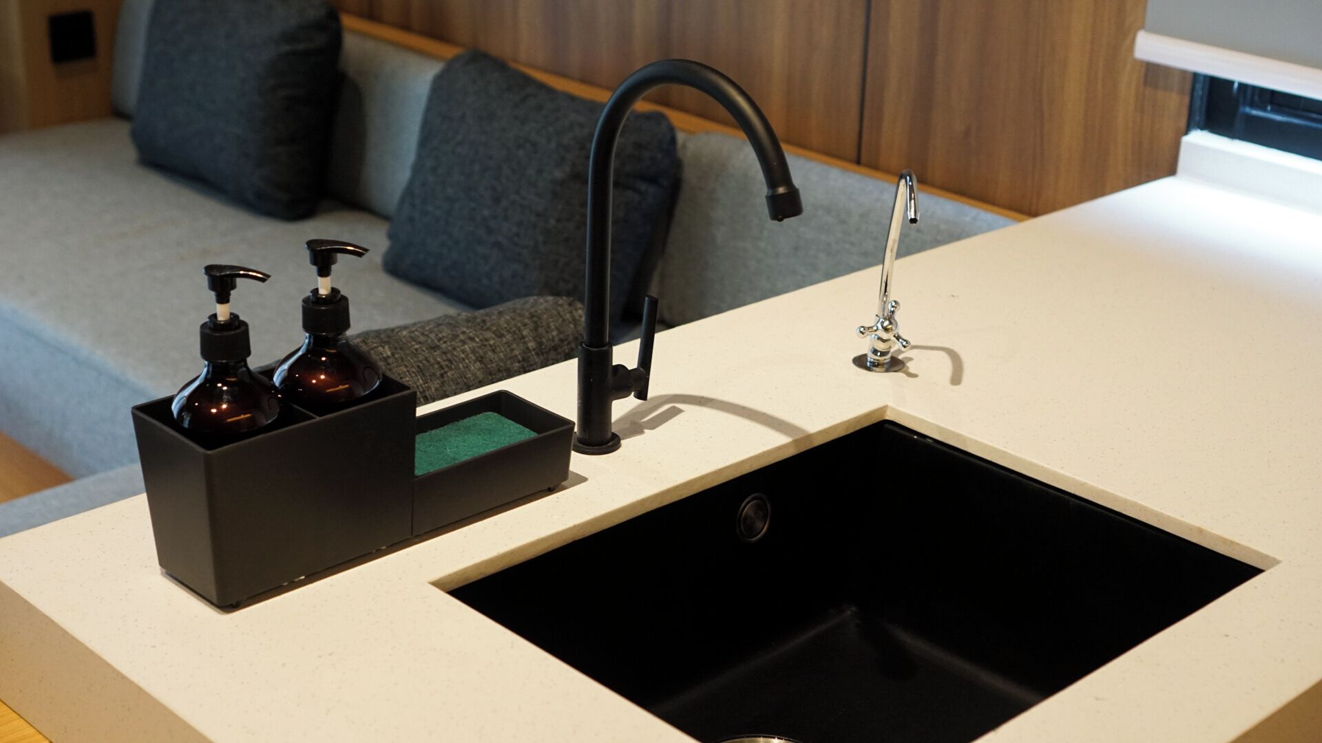 A kitchen with a black sink, a faucet, and a soap dispenser.