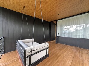 A modern room with a hanging chair, wooden flooring, and a large window with curtains. - Kanana Retreat Coban Rondo (Pujon)
