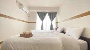 Ein Hotelzimmer mit einem großen Bett, einem Nachttisch und einem Fenster mit Vorhängen.