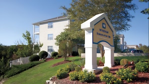 Señal de Wyndham Branson at the Falls, un edificio de varios pisos con un jardín bien cuidado y un estacionamiento.