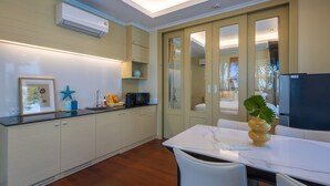 Une cuisine moderne avec des meubles blancs, un plan de travail en marbre et un coin repas comprenant une table et des chaises blanches.