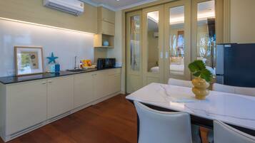 A modern kitchen with white cabinetry, a marble countertop, and a dining area with a white table and chairs.