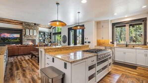 A modern kitchen with granite countertops, a central island, white cabinetry, and pendant lighting.