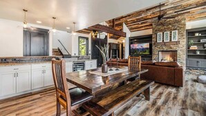 A spacious living area with a wooden dining table, a fireplace, and a stone accent wall.
