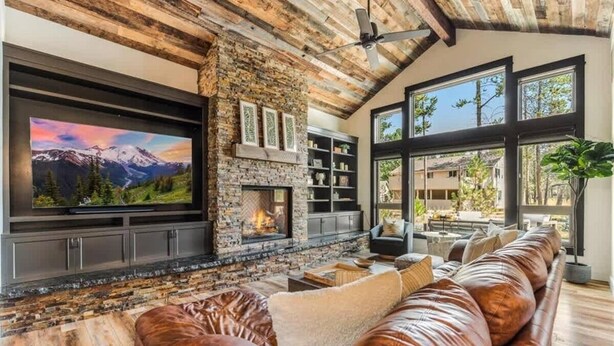 A cozy living room with a fireplace, leather sofa, and a large TV.