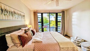 A bedroom with a bed, a ceiling fan, a window with curtains, and a view of the outside. - Rooftop Terrace Condo with Golf Views – 5-Min Walk to Palmas del Mar Beach FL671 (Humacao)