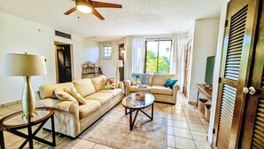 A living room with two sofas, a coffee table, a lamp, and a ceiling fan. - Rooftop Terrace Condo with Golf Views – 5-Min Walk to Palmas del Mar Beach FL671 (Humacao)