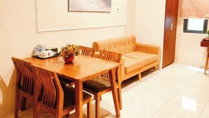A dining area with a wooden table and chairs, a sofa, and a framed picture on the wall. - New Era Hotel & Apartments (Da Nang)