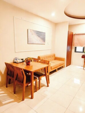 Un área de comedor con una mesa y sillas de madera, un sofá y un cuadro en la pared.