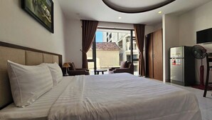Een hotelkamer met een groot bed, een bureau, een stoel, een koelkast en een televisie.