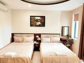 Habitación de hotel con dos camas, un cuadro en la pared, un escritorio con una silla y una ventana con cortinas.