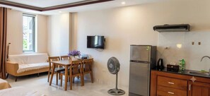 Une chambre d’hôtel compacte comprenant un coin repas, un canapé, une télévision, un réfrigérateur et une kitchenette.