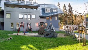 Ein modernes Gebäude mit grauer Fassade, zahlreichen Fenstern und einem geneigten Dach.