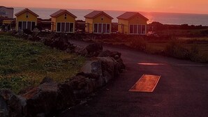 Una hilera de casas de playa amarillas con un atardecer de fondo.