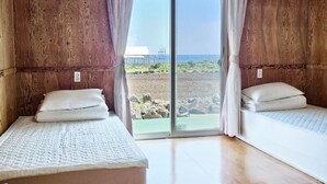 Habitación con dos camas, paredes de madera y vista al mar.