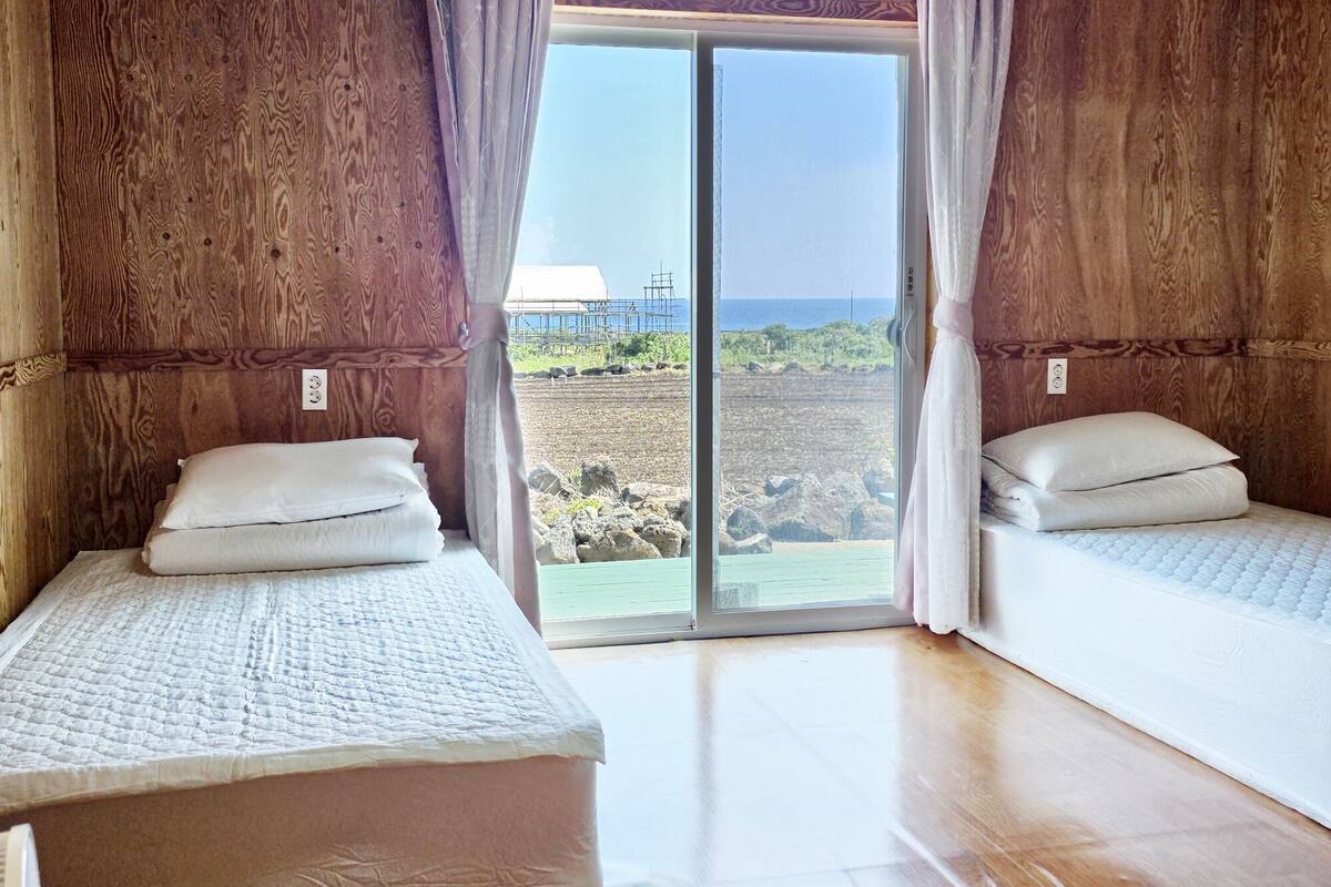 Habitación con dos camas, paredes de madera y vista al mar.