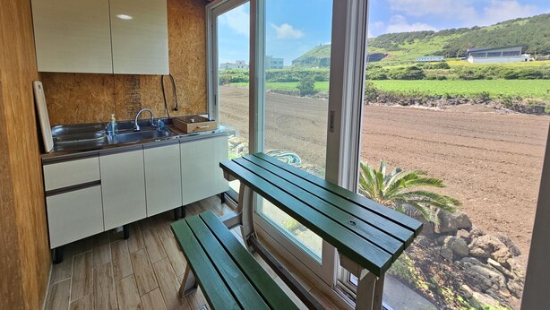 Cocina con techo de madera, armarios blancos y un amplio ventanal con vistas al paisaje rural.