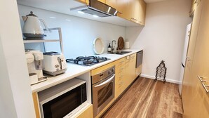 A compact kitchen with a gas stove, microwave, toaster, and a coffee maker. - Sunlit & Peaceful Contemporary Apartment (Randwick)