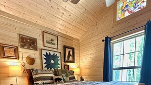 Een houten slaapkamer met een bed, nachtkastjes, een raam en decoraties aan de muur.