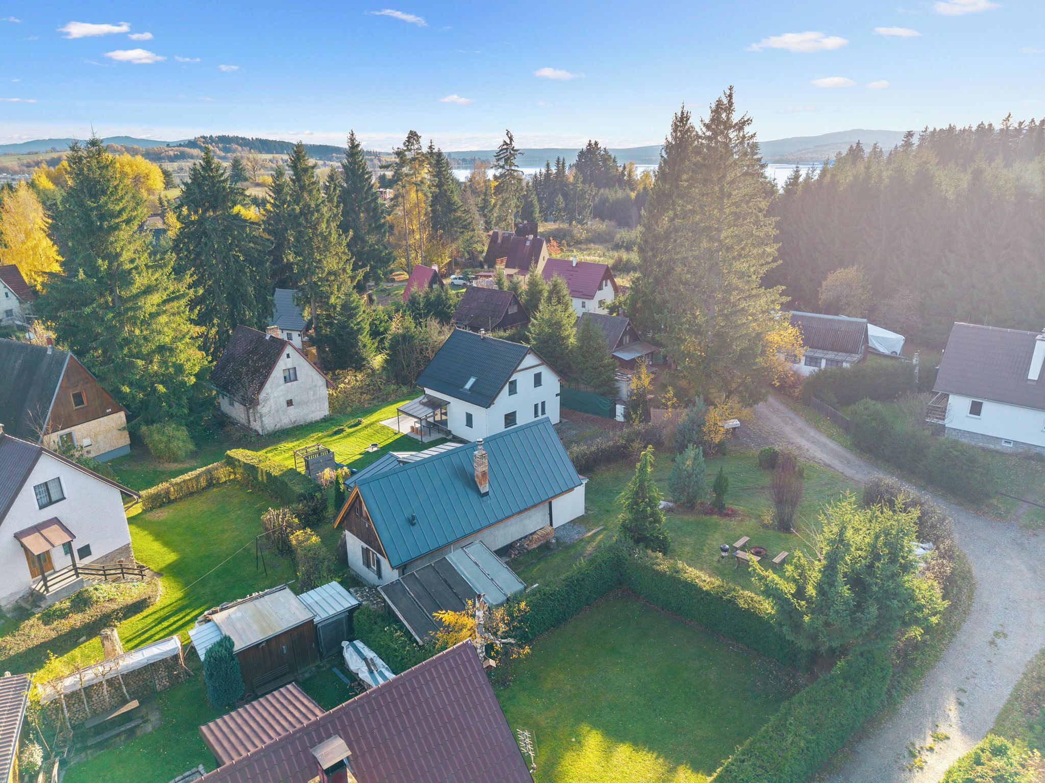 A residential area with houses, a clear sky, and a body of water in the distance.
