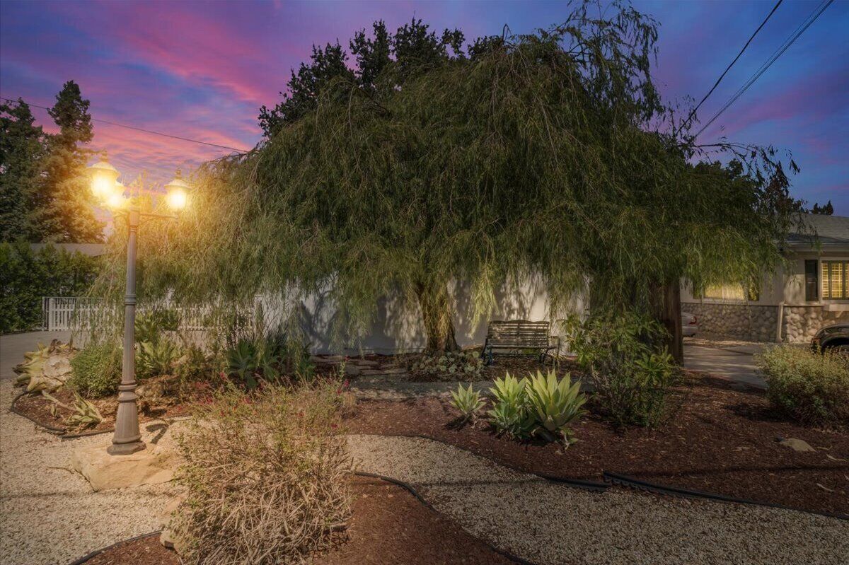 Un jardín ajardinado con un banco, una farola y una casa con fachada de piedra.