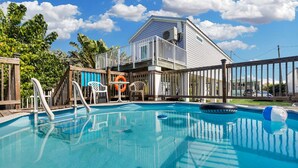 Une piscine avec une terrasse en bois, un poste de surveillance pour les sauveteurs et une bouée de sauvetage.