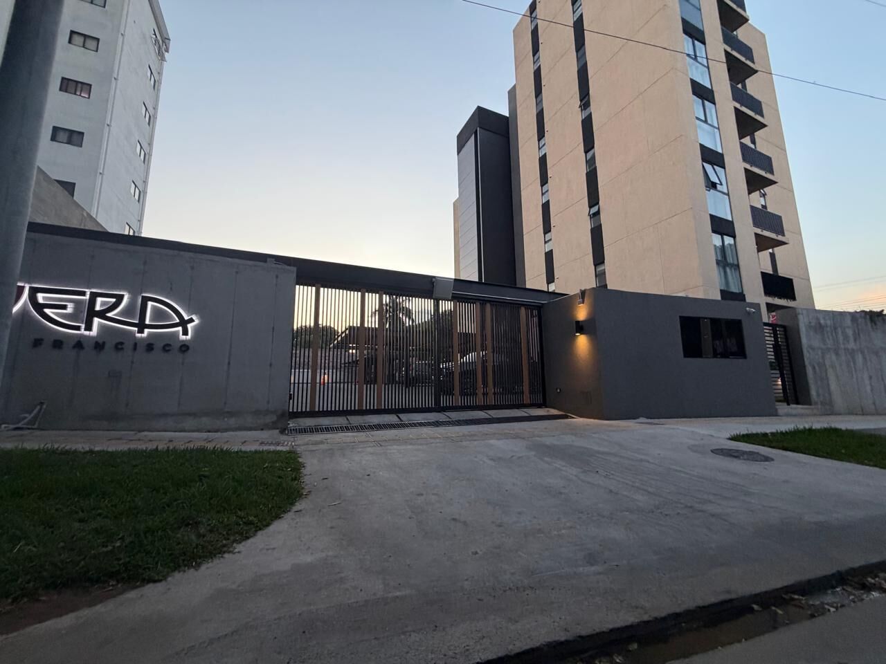 Un edificio con un cancello metallico, un cartello che riporta 'ERP FRANCISCO' e un parcheggio.