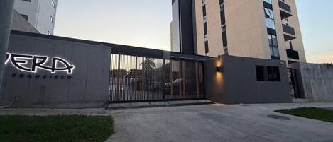 Un edificio con un cancello metallico, un cartello che riporta 'ERP FRANCISCO' e un parcheggio.
