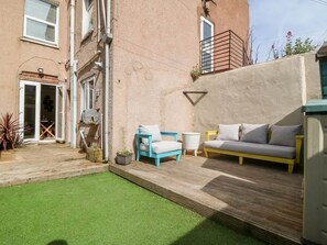 A patio with a blue and yellow sofa, a white sofa, and a small table.