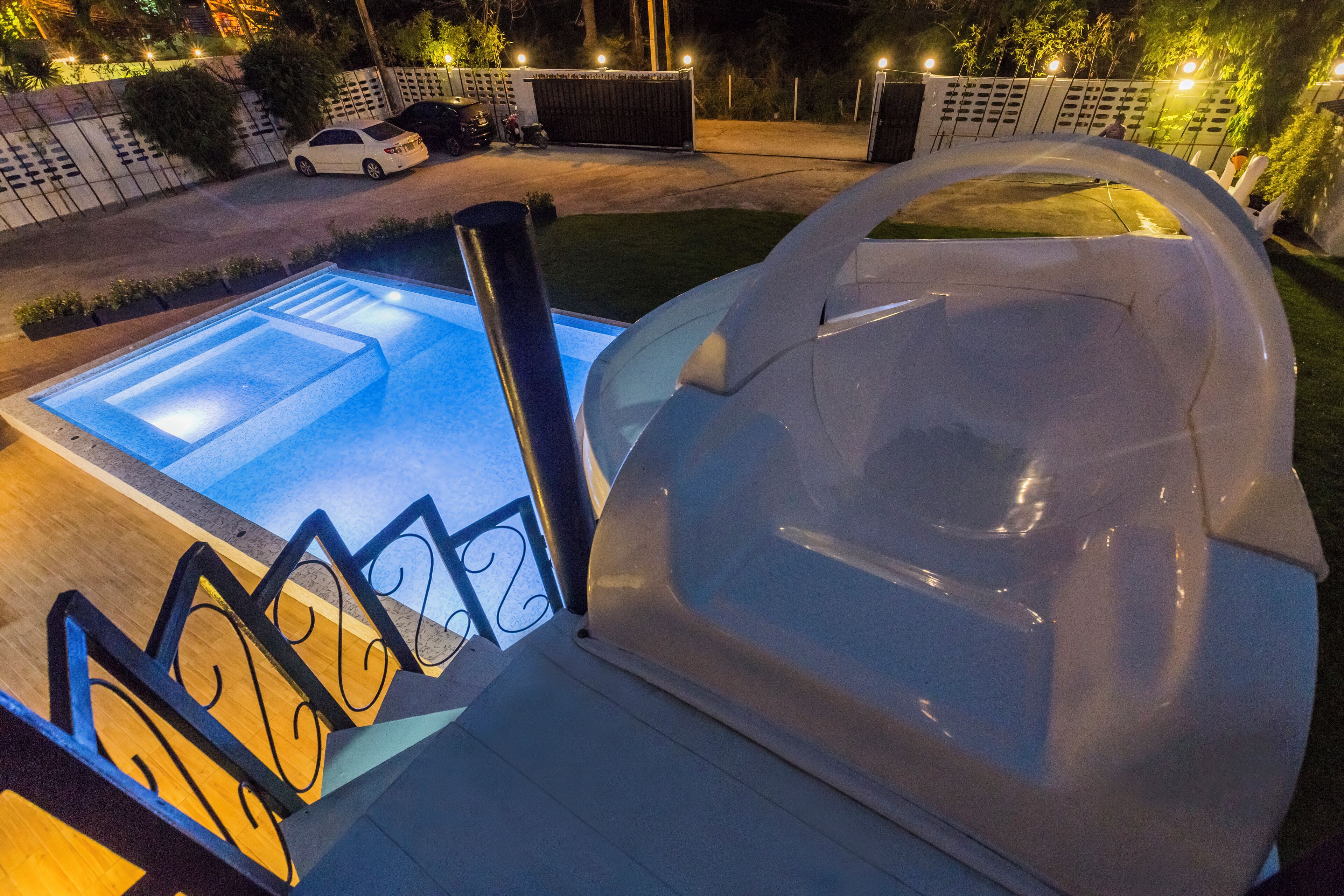 Una piscina con jacuzzi, rodeada por una terraza con barandilla.