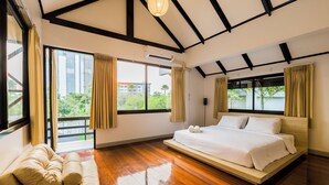 A spacious bedroom with a large bed, a sofa, and a balcony with curtains.