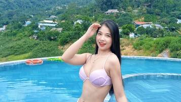 A person standing by a swimming pool with a mountainous landscape in the background.