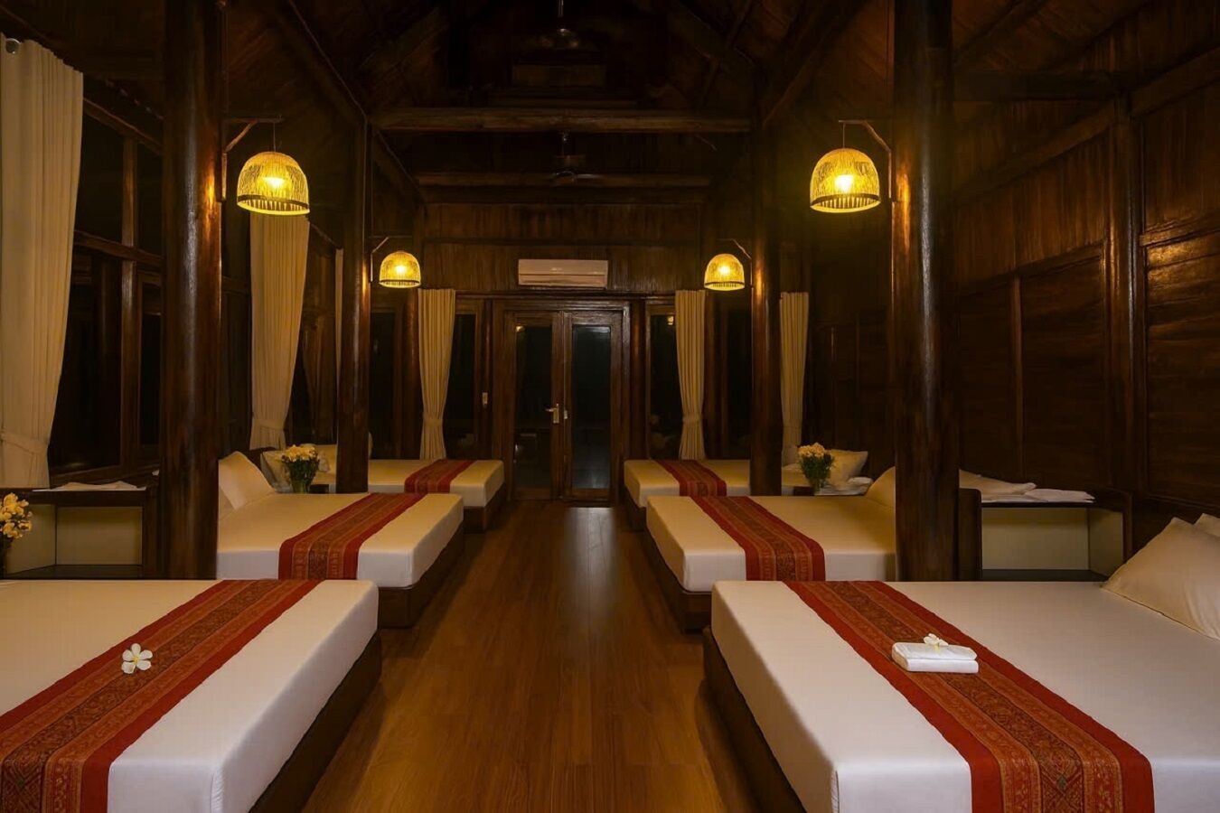 A hotel room with two beds, wooden walls, and a hallway leading to another room.