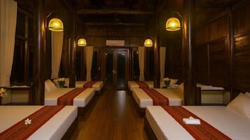 A hotel room with two beds, wooden walls, and a hallway leading to another room.