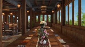 A spacious room with wooden beams, large windows, and a central table with a floral arrangement.