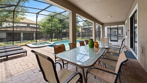 A covered patio with a glass table and chairs, a pool, and a view of a residential area. - Resort Stay w/ Pool & Amazing Amenities (Davenport)