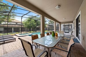 Une terrasse extérieure avec une table en verre, des chaises et une piscine.