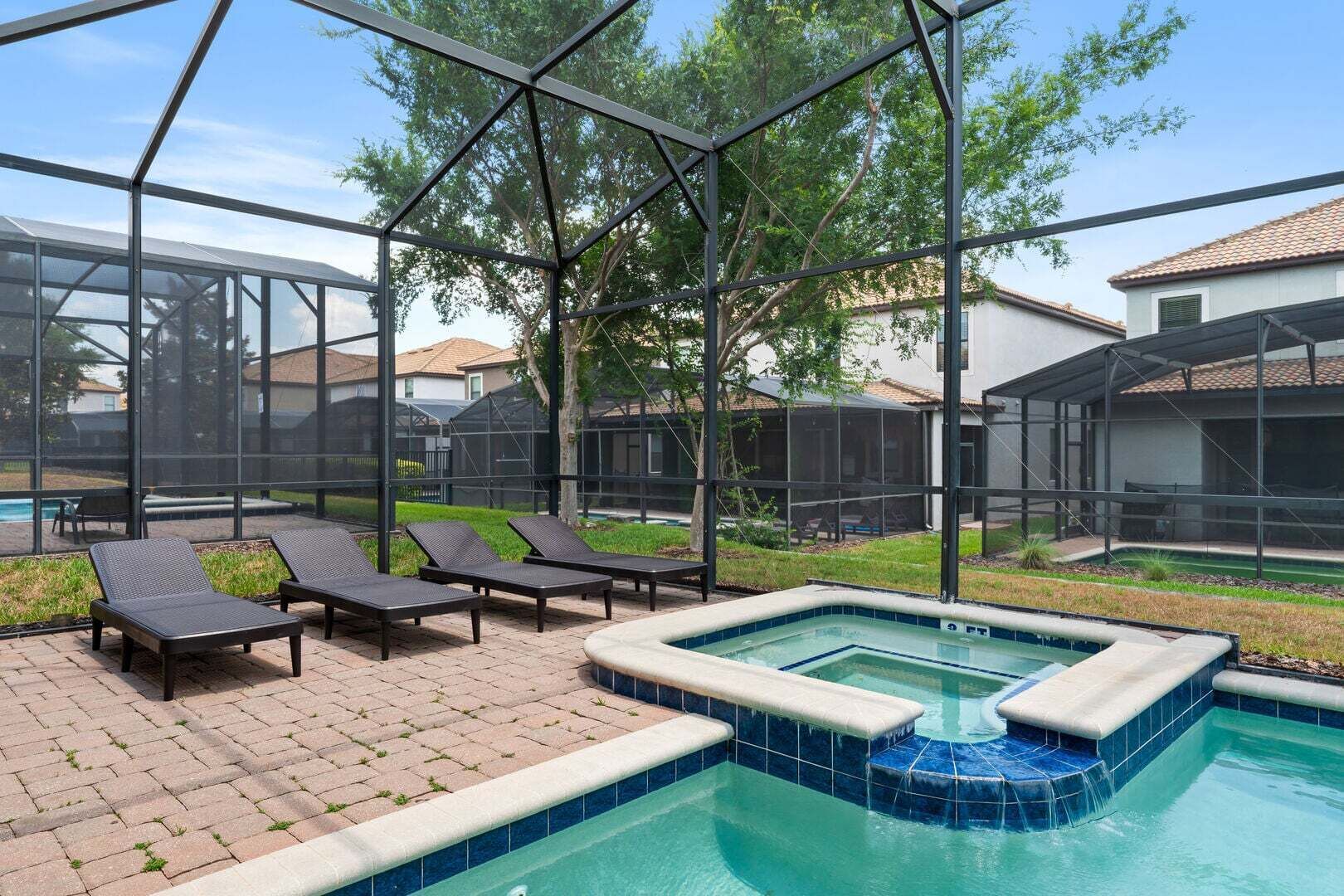 Un área de piscina con sillones de descanso, un jacuzzi y una estructura de vidrio.