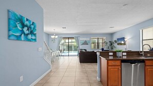 A spacious kitchen with a dishwasher, a dining area with chairs, and a living room with a couch. - Resort Stay w/ Pool & Amazing Amenities (Davenport)