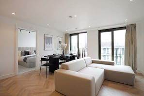 A modern hotel room with a sofa, dining table, and artwork on the walls.