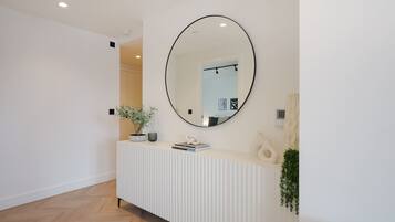 A modern reception area with a white console, a large round mirror, and a potted plant.