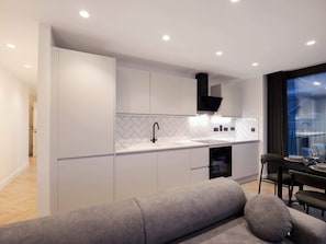 Une cuisine moderne avec des meubles blancs, un robinet noir et un dosseret en carreaux disposés en motif chevrons.