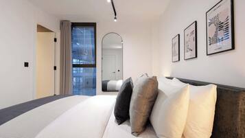 A modern bedroom with a large bed, a mirror, and framed artwork on the wall.