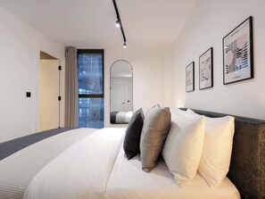 Ein modernes Schlafzimmer mit einem großen Bett, einem Spiegel und gerahmten Kunstwerken an der Wand.