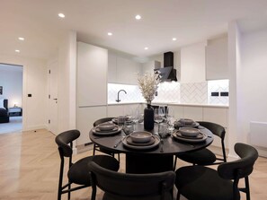 Una cocina moderna con una mesa de comedor para seis personas, armarios blancos y un jarrón negro con flores blancas.