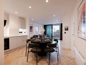 A modern dining area with a round table, chairs, and a vase of flowers.